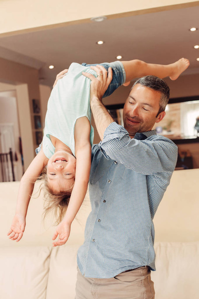 Father and daughter girl kid at home spending time together. Parent playing with child. Family people having fun hugging and laughing. Real people lifestyle. Fathers day holiday concept. - Photo, image