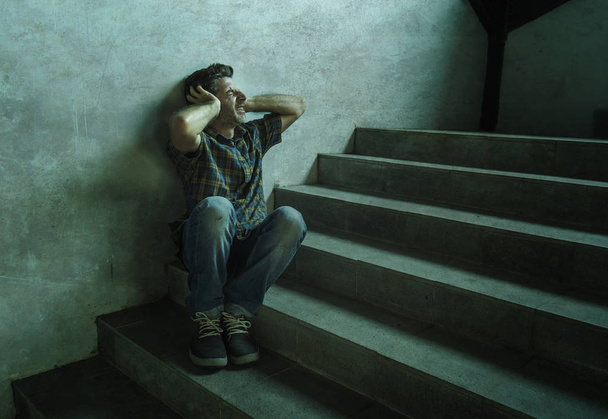retrato dramático de un hombre joven deprimido y paranoico sentado al aire libre en la escalera de la esquina de la calle Grunge oscuro sintiéndose enfermo sufriendo depresión problema y crisis de ansiedad
 - Foto, Imagen