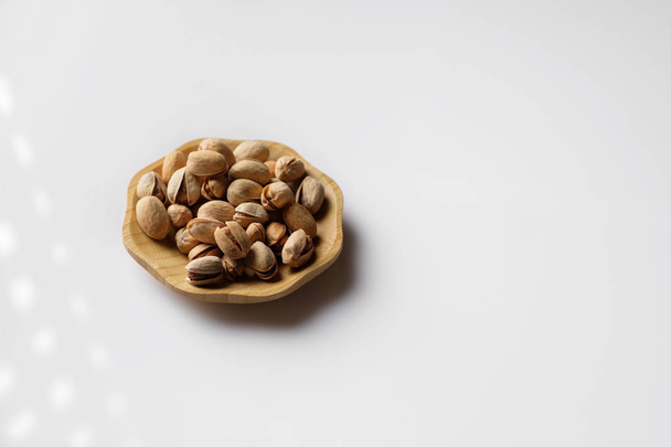 wood plate of salted pistachio nuts - Foto, immagini