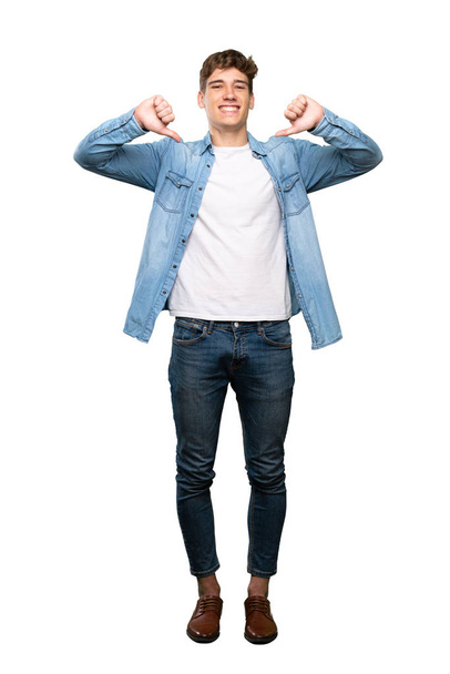 A full-length shot of a Handsome young man showing thumb down over isolated white background - 写真・画像