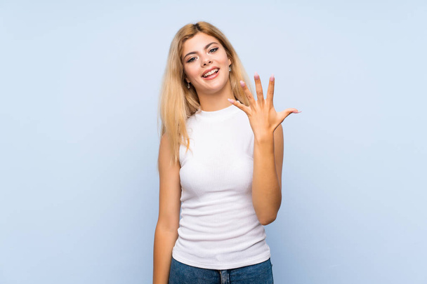 Teenager girl over isolated blue background making the gesture of madness putting finger on the head - Photo, image