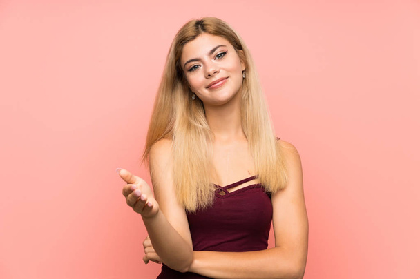 Teenager girl over isolated pink background handshaking after good deal - Foto, afbeelding