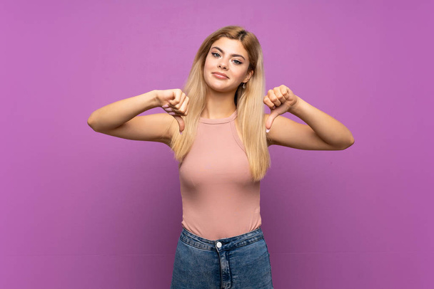 adolescente ragazza oltre isolato viola sfondo mostrando pollice verso il basso
 - Foto, immagini