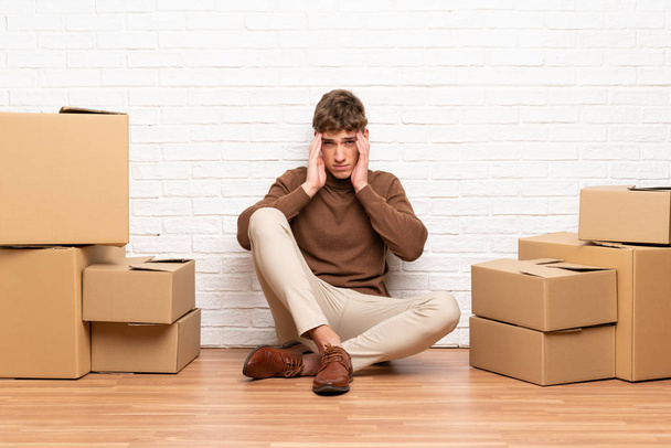 Csinos fiatalember mozog az új otthont dobozok között boldogtalan és frusztrált valami. Negatív arckifejezés - Fotó, kép