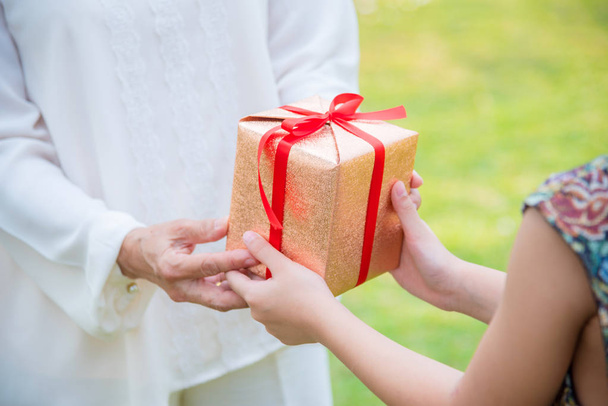 Nahaufnahme auf junge Mädchen Hände geben Geschenk-Box für ältere Frau  - Foto, Bild