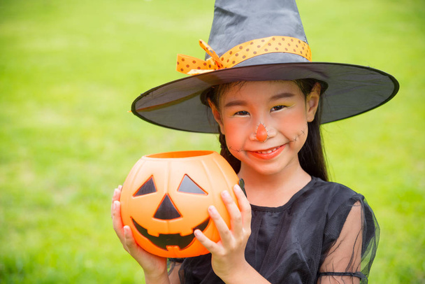 Маленька азіатська дівчинка в костюмі відьми святкують Хеллоуїн на відкритому повітрі
  - Фото, зображення