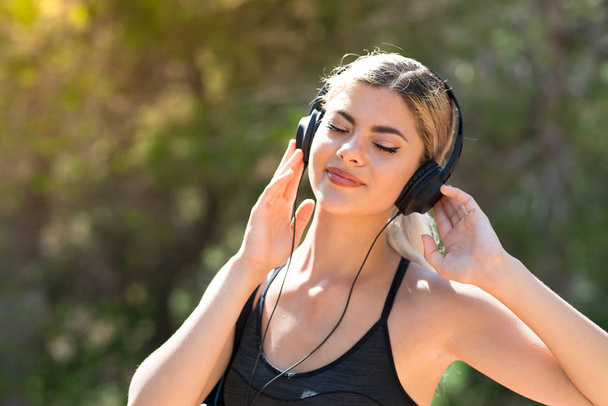 Teini-ikäinen urheilu tyttö tekee urheilua ulkona kuunnella musiikkia kuulokkeet
 - Valokuva, kuva