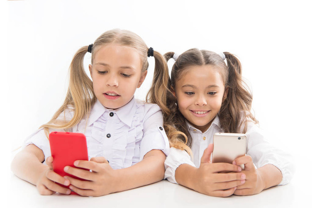 Smart pupils. Little pupils texting message during class isolated on white. Cute lyceum pupils diving deep into smartphone lessons. Small pupils using mobile phones in classroom - Φωτογραφία, εικόνα