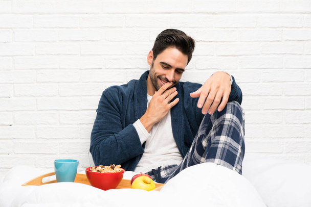 Man in bed with dressing gown and having breakfast smiling a lot - Photo, Image