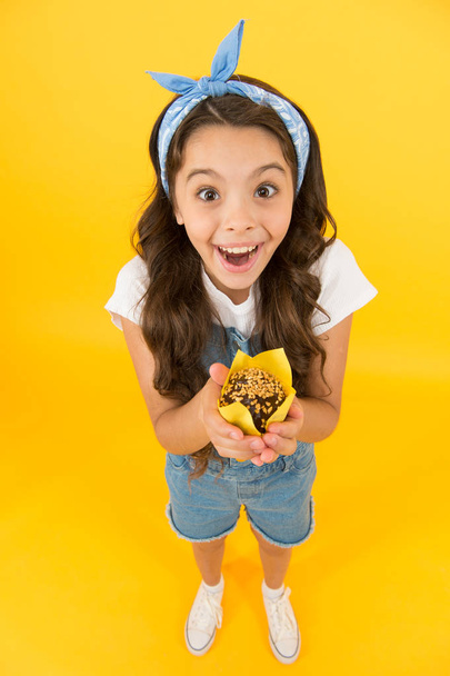 Treat someone with sweets. Yummy cupcake. Homemade muffin. Sweet tooth concept. Kid girl hold appetizing muffin. Gluten free recipe. Delicious cupcake. Little child with muffin on yellow background - 写真・画像