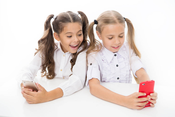 Blog for students. Little children typing new blog post from smartphone. Small bloggers keeping class blog. Smart girls posting their blog on online social network through mobile device - Foto, Imagen