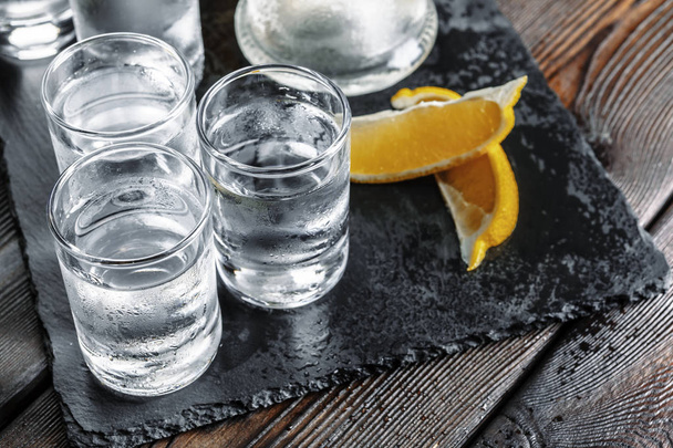 Vodka in shot glasses on rustic wood background - Foto, afbeelding