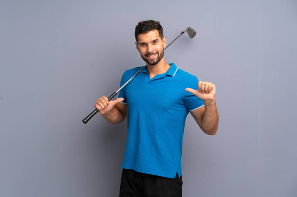 Handsome young man playing golf proud and self-satisfied - Fotó, kép
