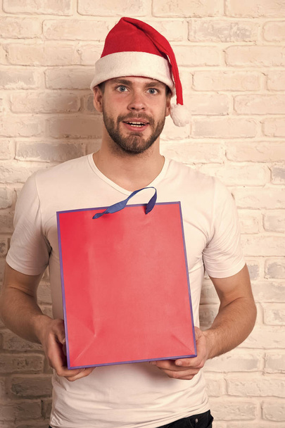 man in santa hat hold christmas present. online christmas shopping. Happy new year, copy space. delivery christmas gifts. The morning before Xmas. happy santa man. Office christmas party - Fotoğraf, Görsel