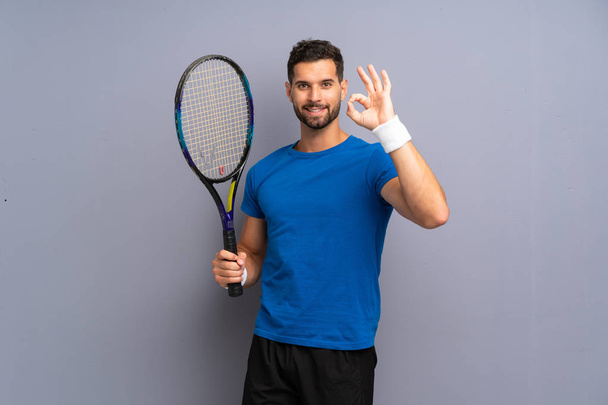 Handsome young tennis player man showing ok sign with fingers - Photo, Image