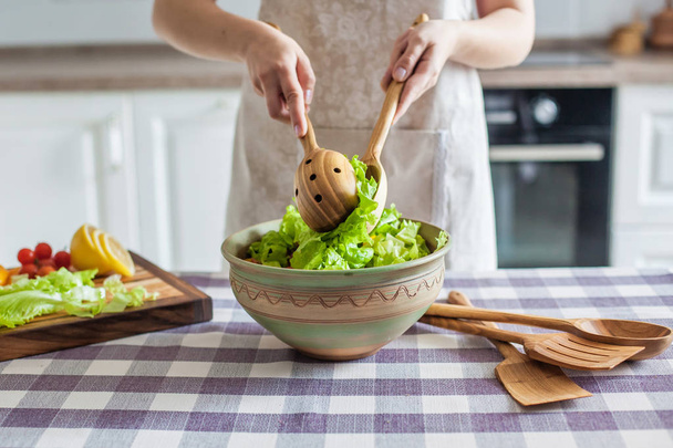 Ernährung. junge hübsche Frau in grünem Hemd steht und bereitet den Gemüsesalat in Schüssel für gute Gesundheit in der modernen Küche zu Hause, gesunder Lebensstil, Kochen, gesundes Essen - Foto, Bild