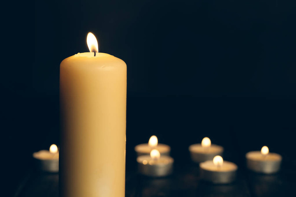 candles burning in darkness over black background. commemoration concept. - 写真・画像