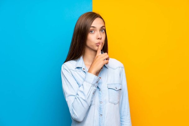 Young woman over colorful background doing silence gesture - Фото, зображення