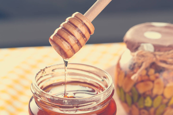 Honey background. Sweet honey in glass jar on wooden background. - Photo, Image
