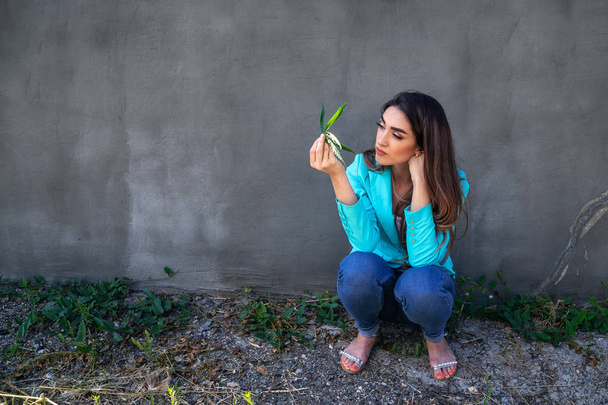 Conceptual photo. Girl with hemp on concrete wall background - Foto, Imagem