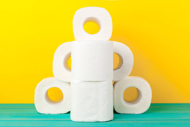Toilet paper rolls stacked against yellow paper background - Foto, Imagem