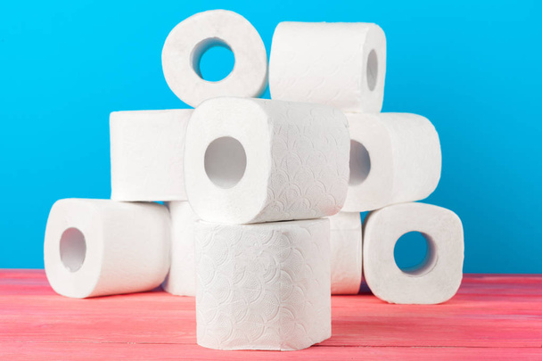 Toilet paper rolls stacked against blue background - Fotoğraf, Görsel