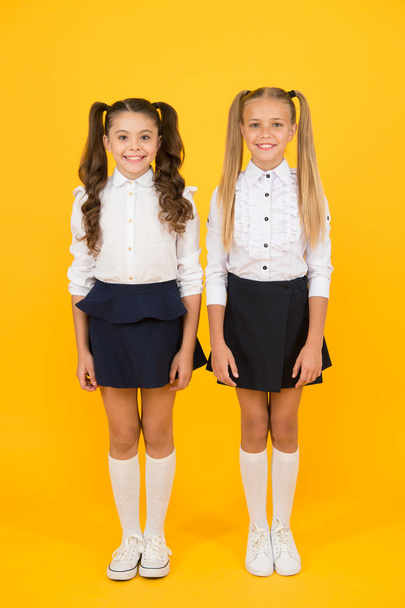 Its important to have friends. Happy small friends. Little school friends smiling on yellow background. Adorable girl friends enjoying their friendship - 写真・画像