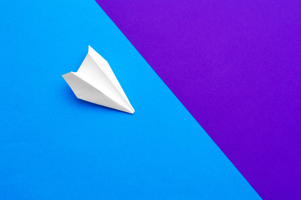 white paper airplane on a color block blue and purple background - Foto, Imagen