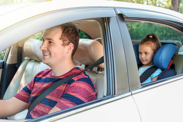 Мужчина за рулём машины с дочерью, пристегнутой ремнем безопасности.
 - Фото, изображение