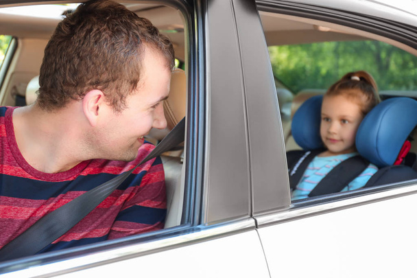 Uomo guida auto con la figlia allacciata al sedile di sicurezza
 - Foto, immagini