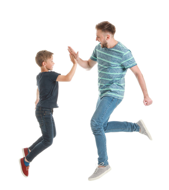 白い背景に互いにハイファイブを与える父と息子をジャンプ - 写真・画像