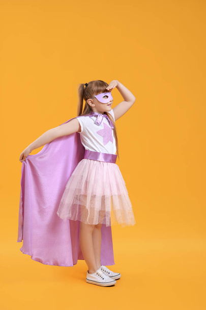 Cute little girl dressed as superhero on color background - Foto, afbeelding