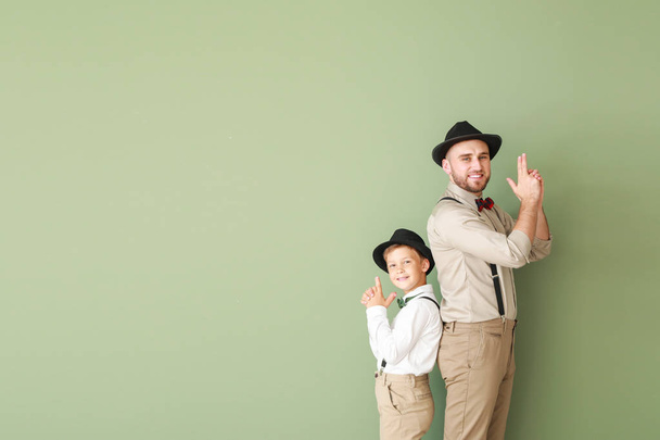 Portrait of fashionable father and son showing "hand pistol" gesture on color background - Photo, Image