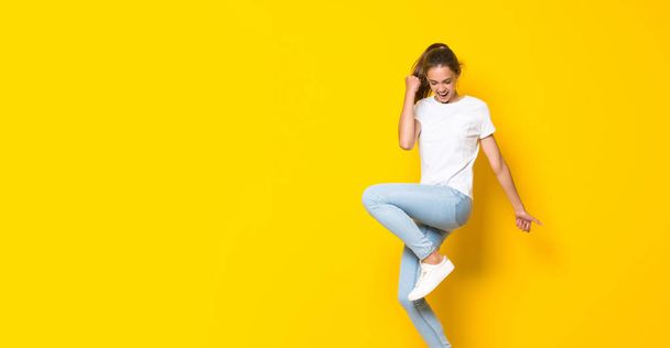Mujer joven saltando sobre la pared amarilla aislada
 - Foto, imagen