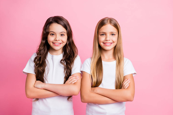 Photo of two nice good friendly girls with their hands folded staring at camera while isolated with pink background - Фото, зображення