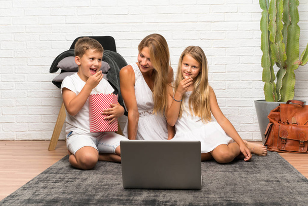 Мать с двумя детьми в помещении и с попкорнами
 - Фото, изображение