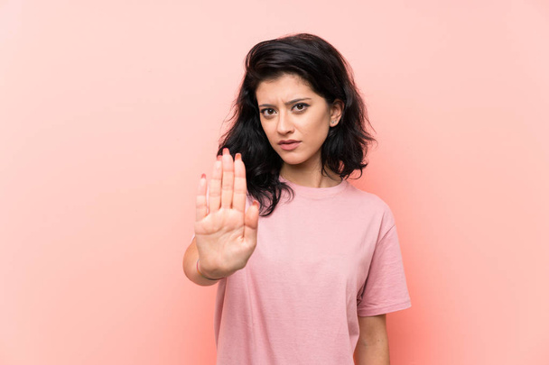 Young woman over isolated pink background making stop gesture with her hand - Foto, Bild