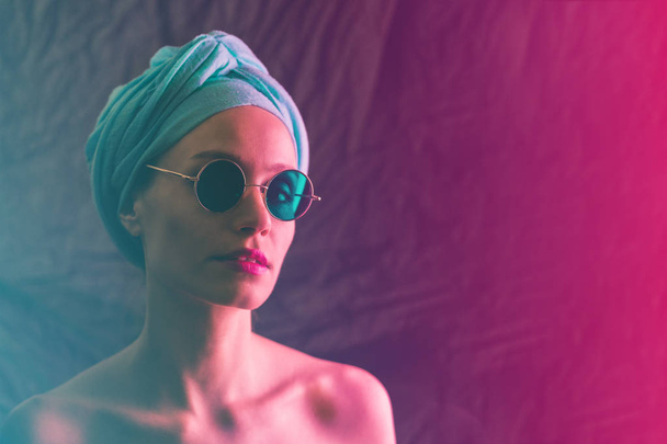 Portrait of girl in neon light, dressed in blue turban on her head and green glasses. - Fotó, kép