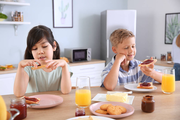 Hassut pienet lapset syövät maukkaita paahtoleipiä keittiössä
 - Valokuva, kuva