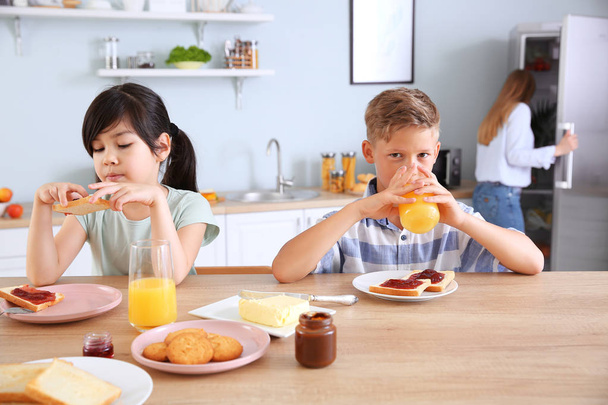 Funny little children eating tasty toasts in kitchen - Photo, Image