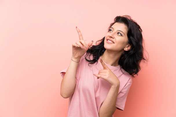 Young woman over isolated pink background pointing with the index finger a great idea - Foto, imagen