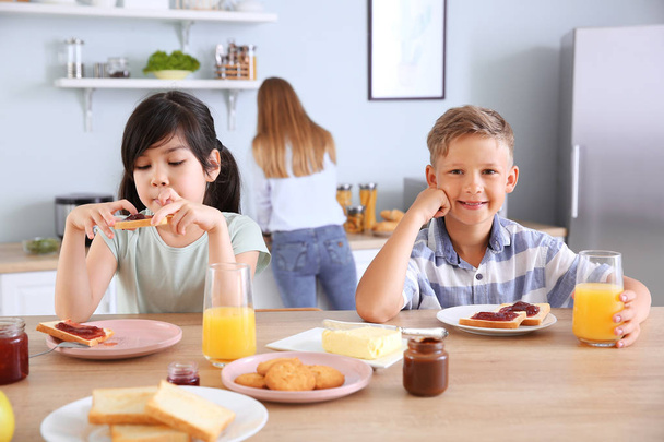 Hassut pienet lapset syövät maukkaita paahtoleipiä keittiössä
 - Valokuva, kuva