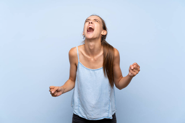 Jovem mulher sobre isolado fundo azul gritando para a frente com a boca aberta
 - Foto, Imagem