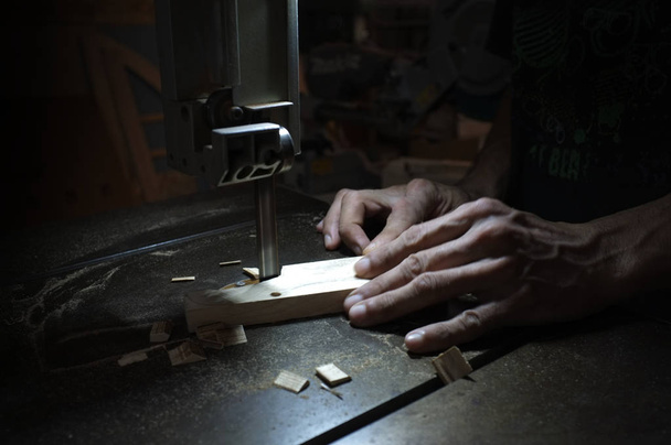 Schreiner, der mit elektrischer Stichsäge und Holz arbeitet. Holzarbeiter, der ein Stück Holz schneidet   - Foto, Bild