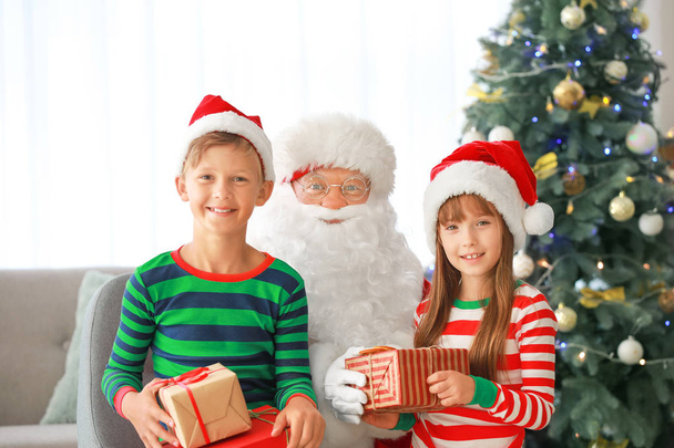 Дід Мороз і його маленькі помічники з подарунками в кімнаті, прикрашену на Різдво - Фото, зображення