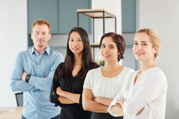 Portrait of young multi-ethnic business team standing together with arms crossed and smiling at camera at office - Photo, Image