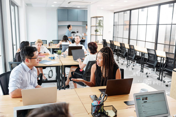 Grupa ludzi biznesu siedzących w miejscu pracy za pomocą komputerów przenośnych w pracy i omawia momenty pracy w nowoczesnym biurze  - Zdjęcie, obraz