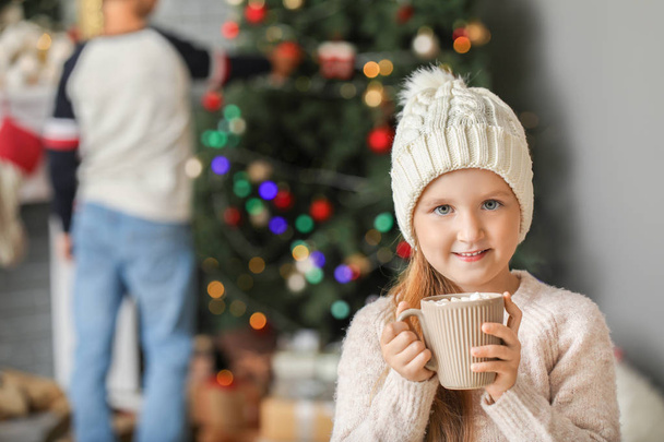 Cute little girl drinking hot chocolate at home on Christmas eve - Fotoğraf, Görsel
