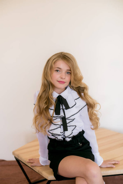 Cute girl with long blond curly hair in school fashion clothes. School fashion in vintage elite style. - Foto, Imagen