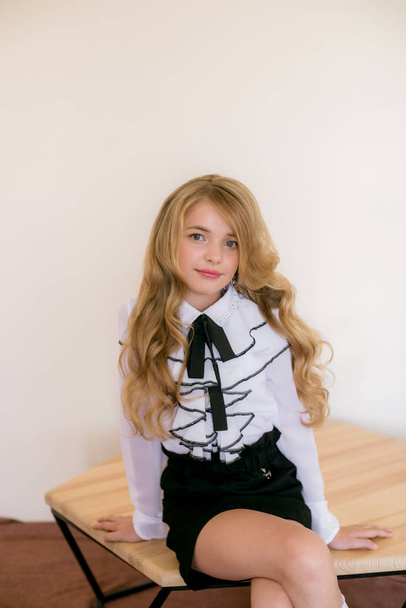 Cute girl with long blond curly hair in school fashion clothes. School fashion in vintage elite style. - Foto, Imagen